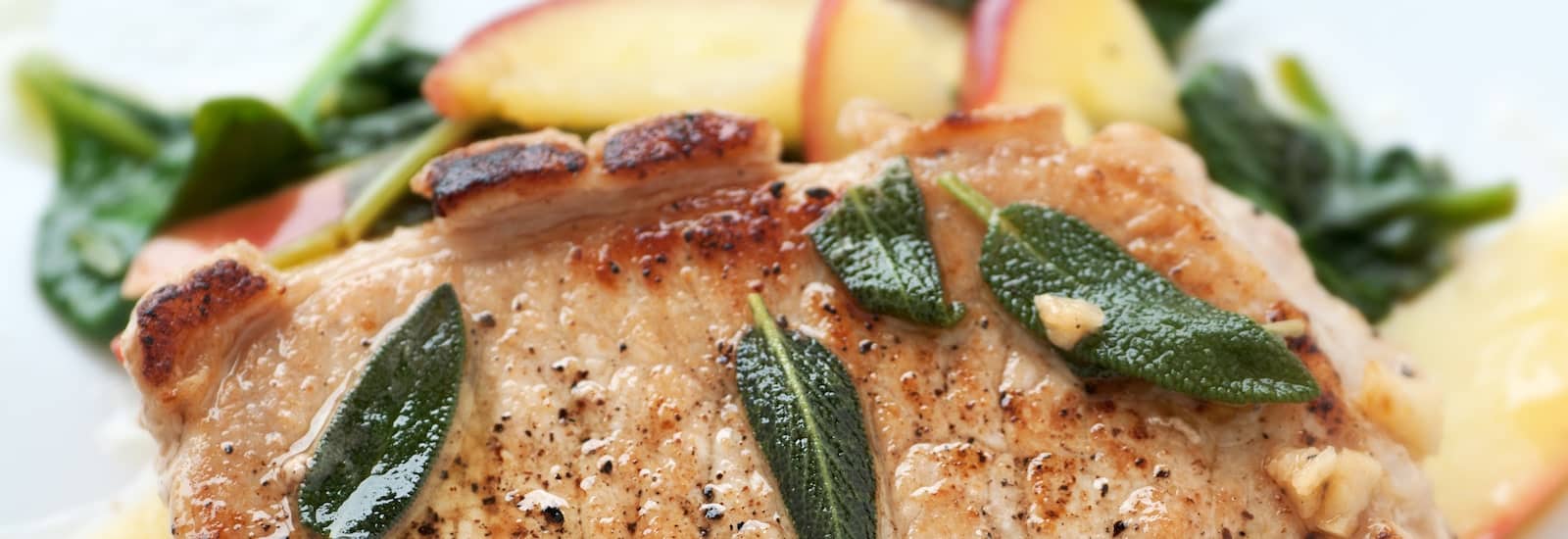 large pork chop with sage and sliced peaches